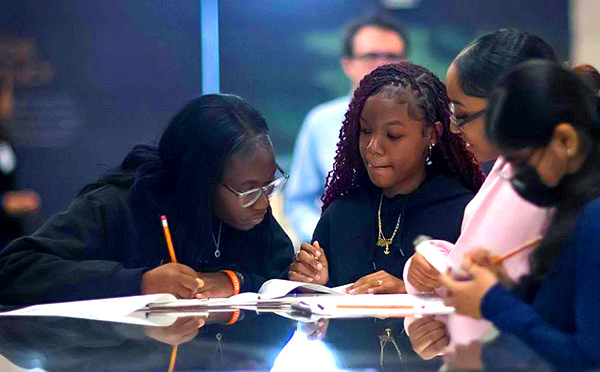 Four students work on an assignment in the New York Fed Museum & Learning Center, as part of the HE3AT program run in partnership with the New York City Department of Education and the Brooklyn South School District.