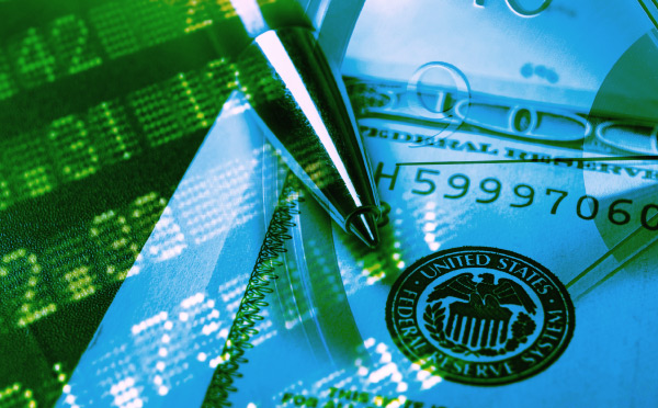 An image composite of numbers on a trading board, a pen and a hundred dollar bill. 