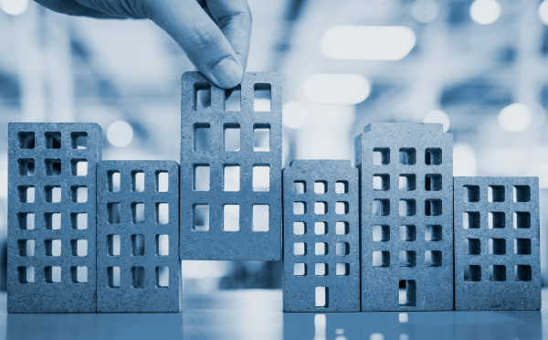close up of hand arranging wooden cube shapes that simulate housing