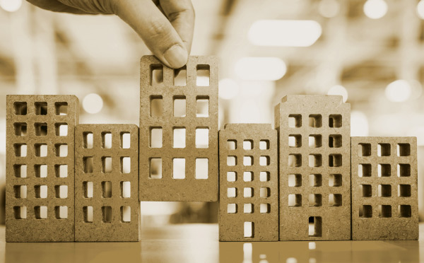 close up of hand arranging wooden cube shapes that simulate housing