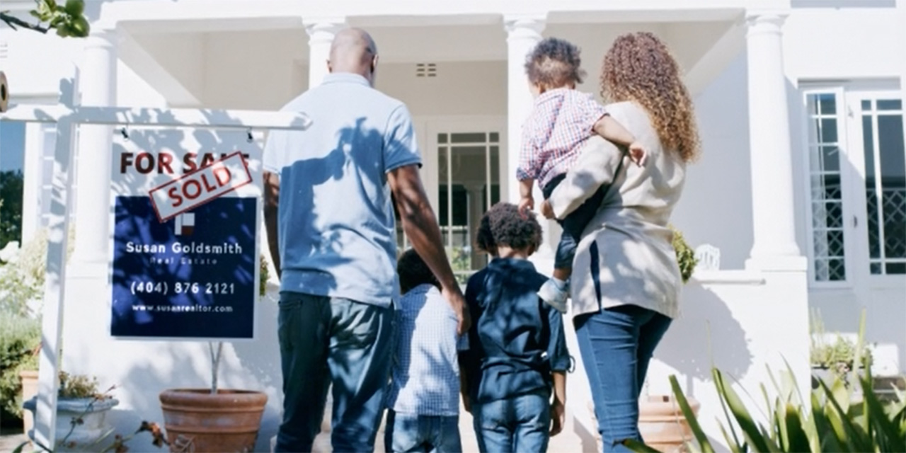 Young family entering home showing sold sign