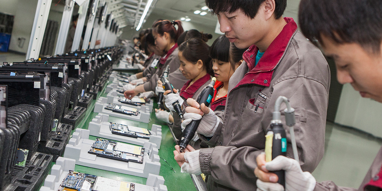 Looking down line of male and females Asian workers assembling high-tech products in factory 