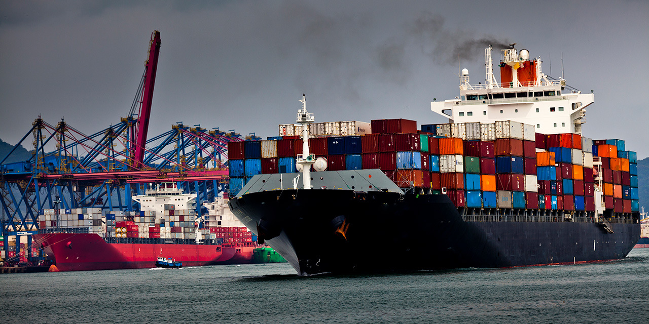 Two large container ships stacked with cargo near an active port