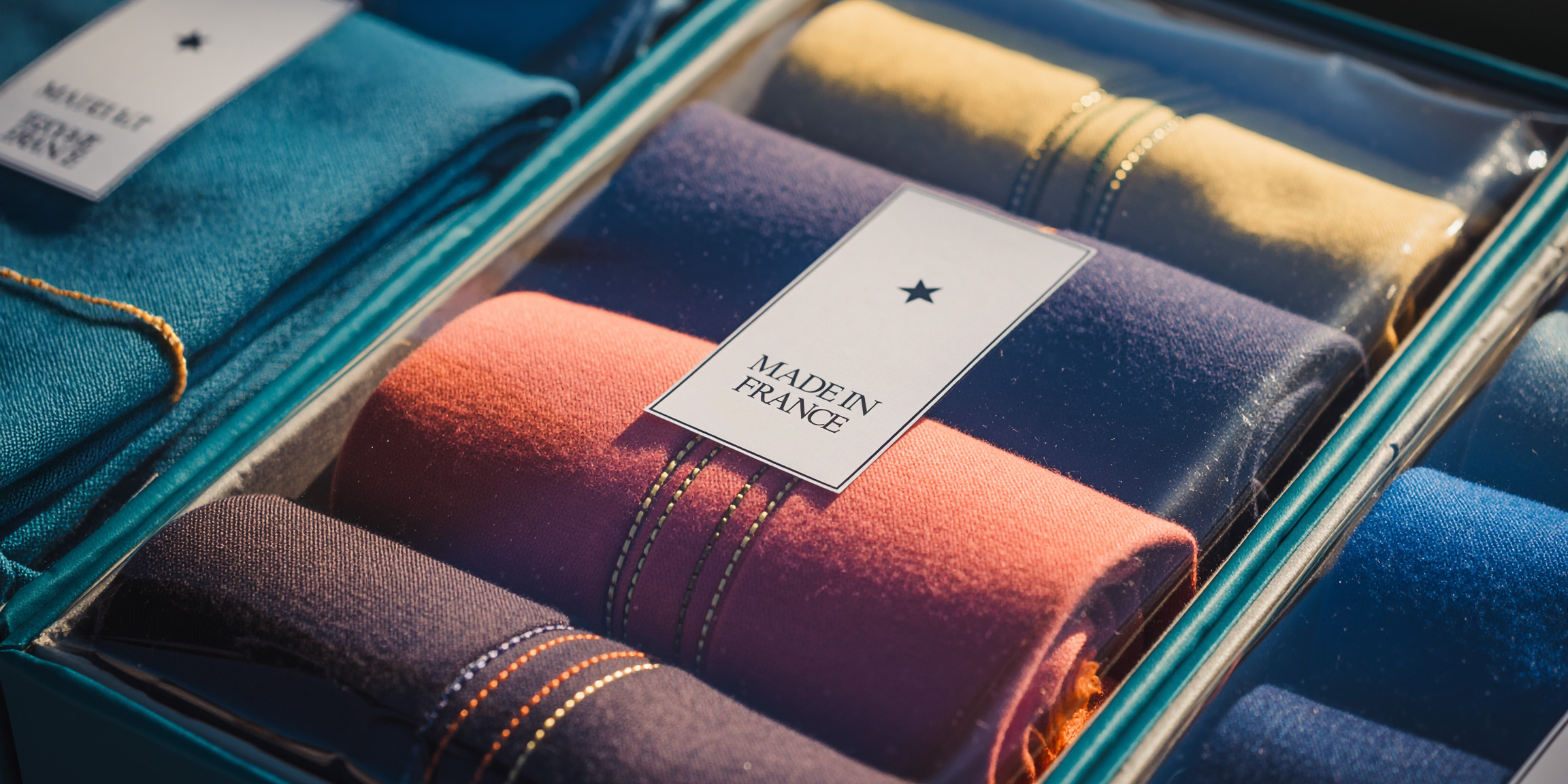 Photo: clothing items rolled in a box with label on it Made in France