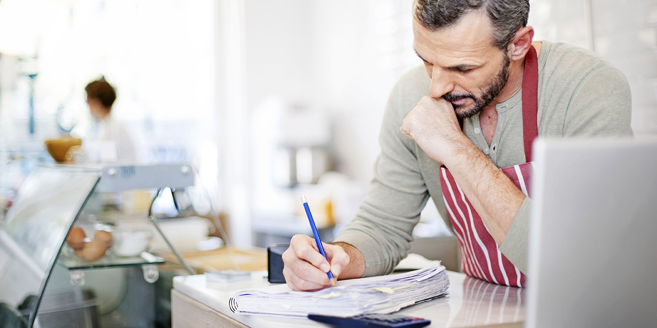 cafe owner focusing on business paperwork behind service counter