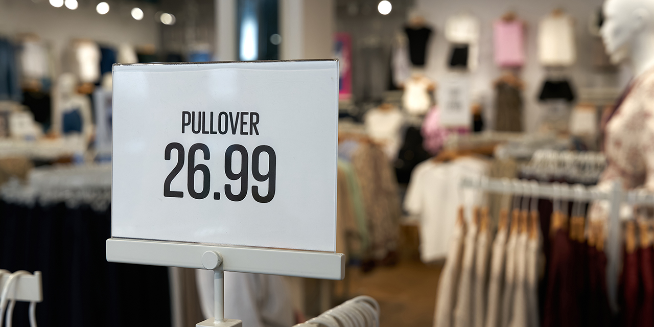 retail sign for pullover priced at 26.99 against background of a store with clothing racks retail sign for pullover priced at 26.99 against background of a store with clothing racks
