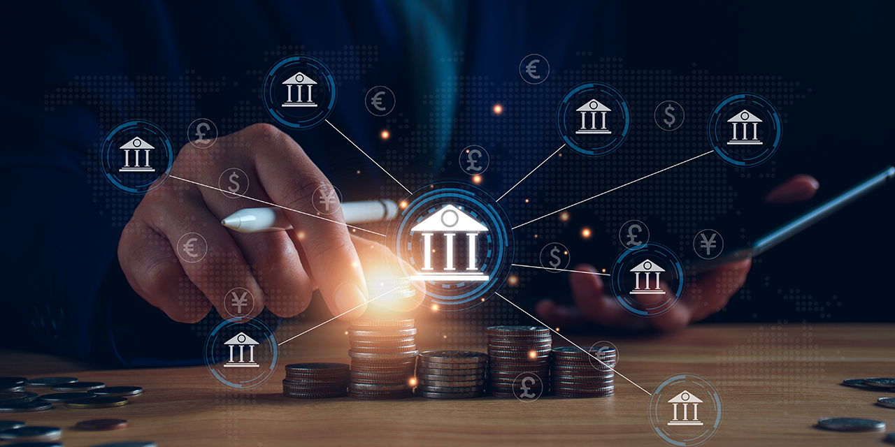 Icons of financial institutions and various currencies connected by lines overlayed on a desk with stacked coins and a person's hand picking up a coin Icons of financial institutions and various currencies connected by lines overlayed on a desk with stacked coins and a person's hand picking up a coin