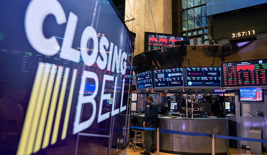 Floor of the stock exchange with a large screen in front that says closing bell.