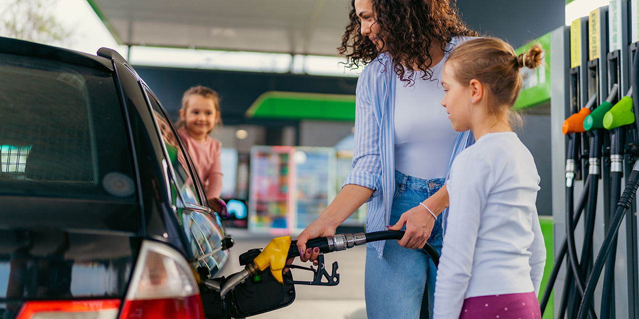 the mother fills the car with fuel at the gas station and talks to her daughters about the upcoming trip